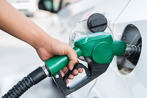 Hand holding a fuel pump going into a car