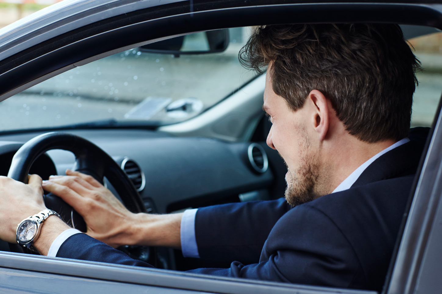 Man pressing his hand on the steering wheel to sound the car horn