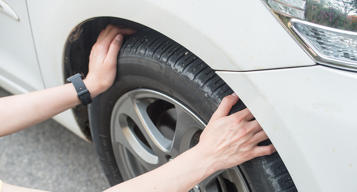 hands touching and checking a car tyre - good driver