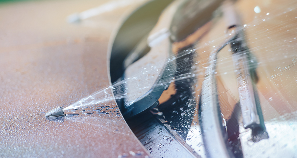 Close up of windscreen washer nozzle spraying windscreen - knowing your vehicle