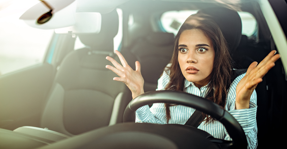 Young woman at steering wheel angered by other drivers - staying in control