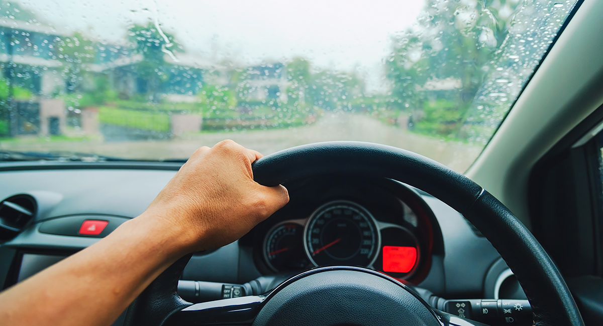 Hand gripping steering wheel in rain