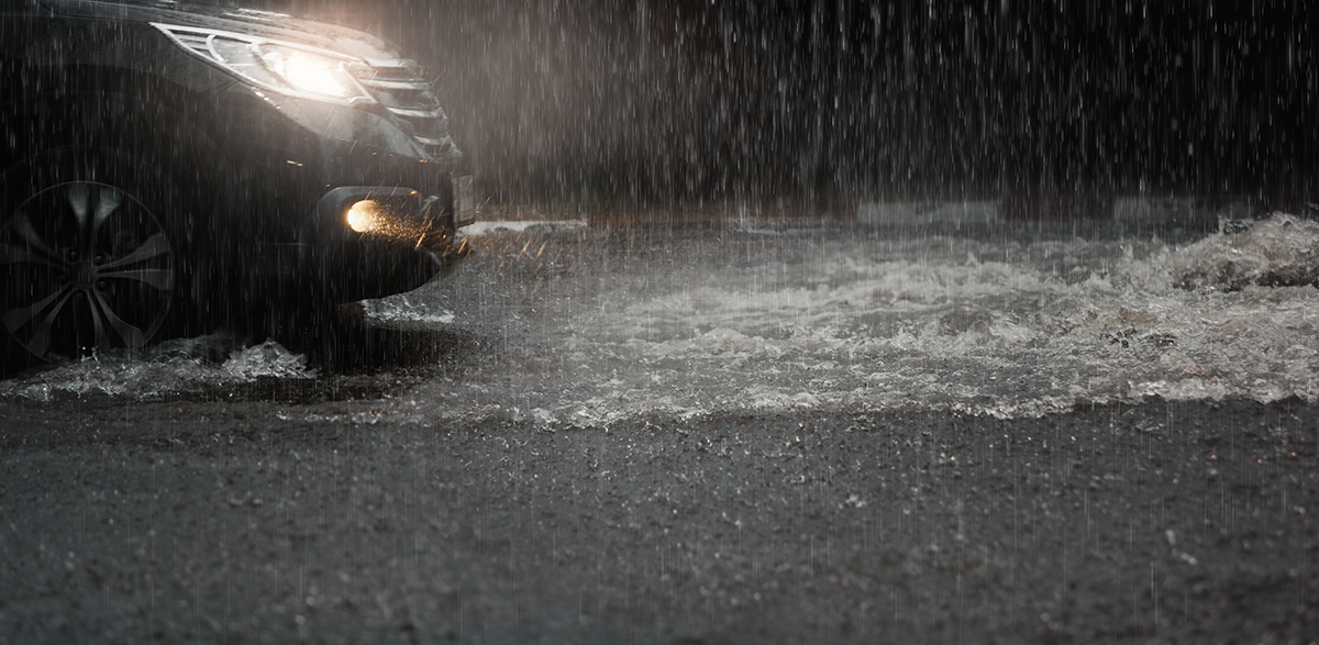Car with headlights on in flooded road in rain storm