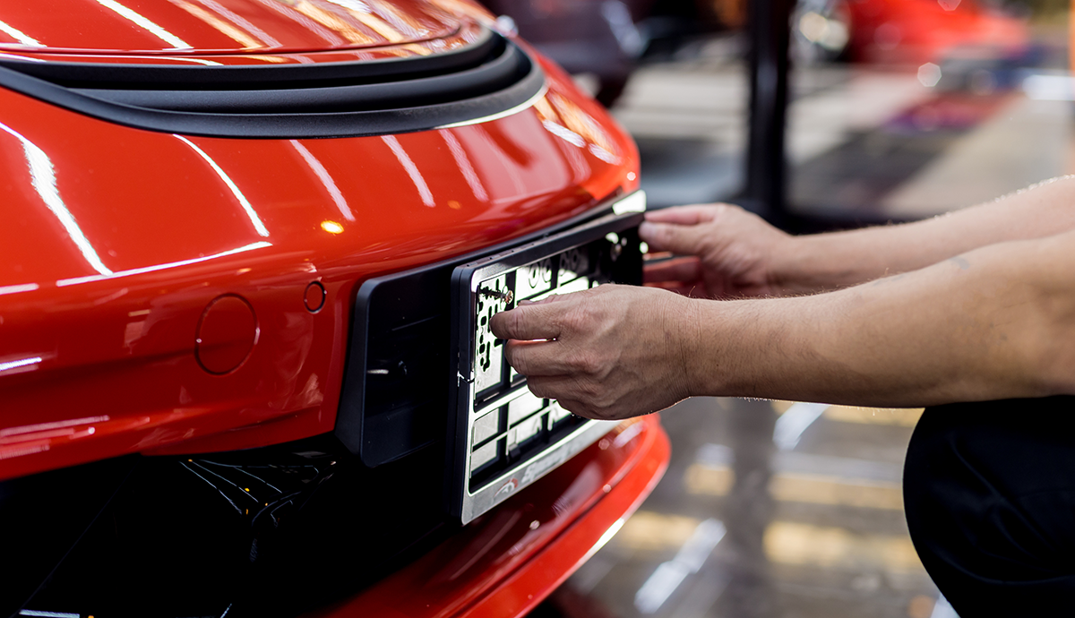 Person replacing a number plate on a car - car cloning crime